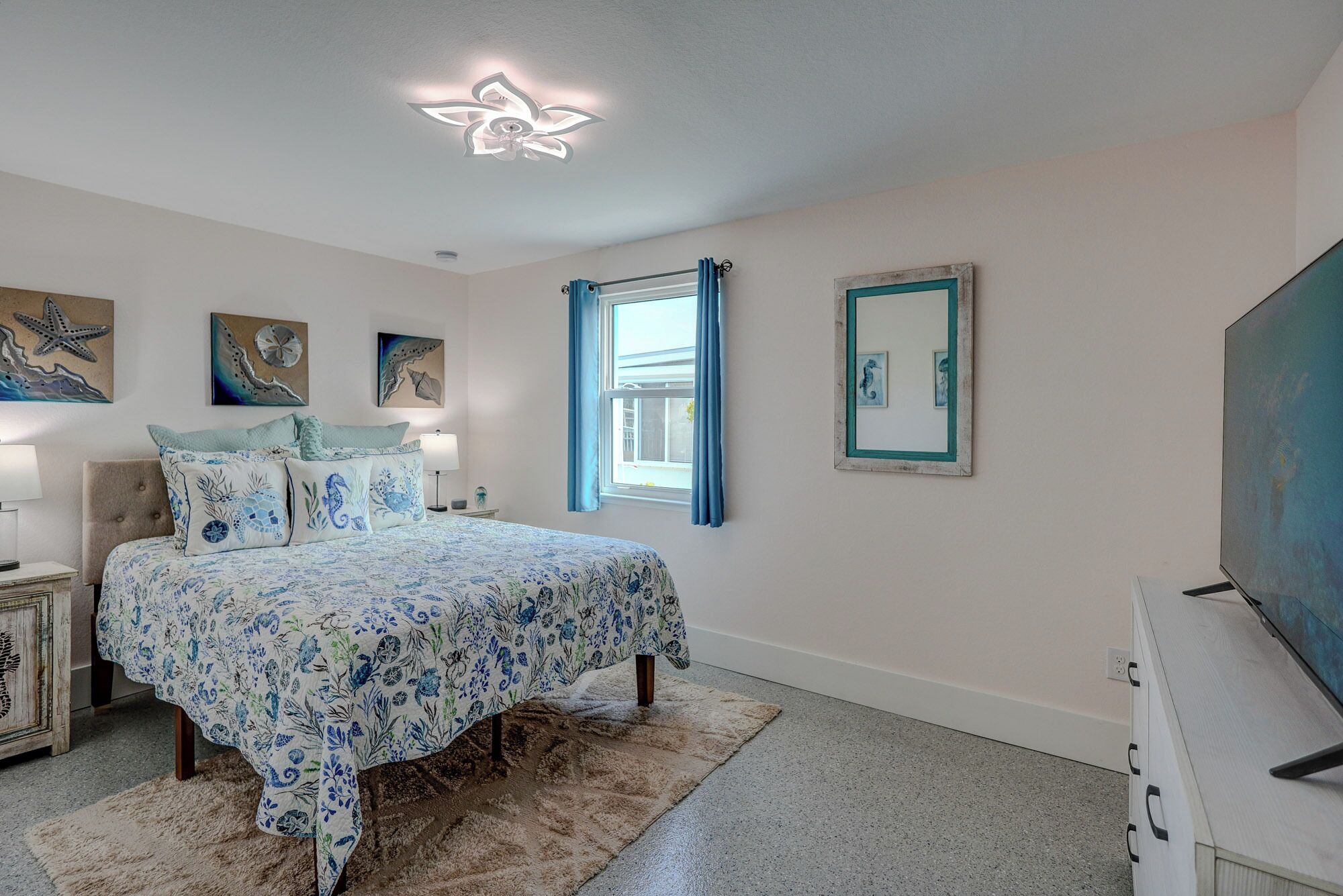 A bedroom with a bed, a nightstand, a dresser, a ceiling fan, and artwork on the walls.