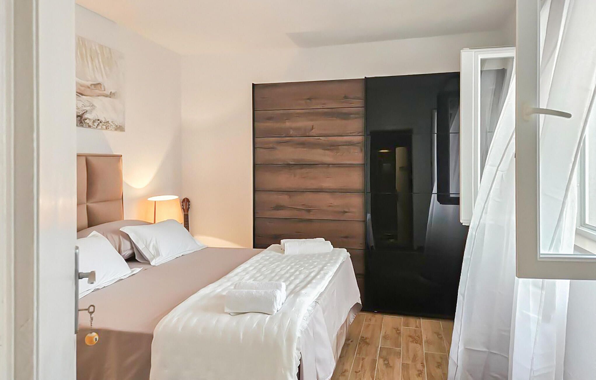 A bedroom with a bed, bedside lamp, and a wooden headboard.