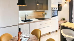 Une cuisine moderne équipée d’un évier, d’une cuisinière et d’un coin repas avec des chaises et une table.