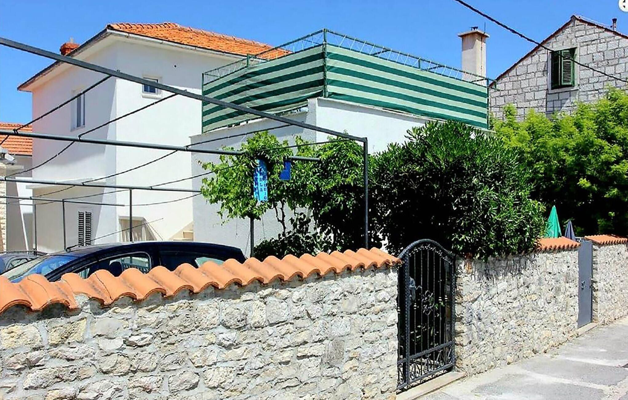 Una casa de dos pisos con un muro de piedra y techo de tejas.