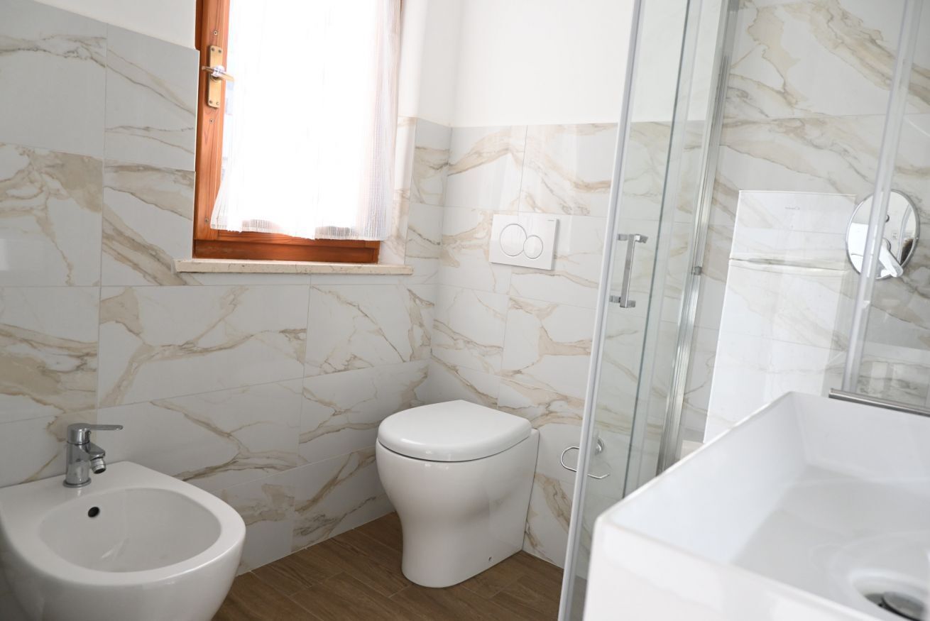 A bathroom with a bidet, toilet, and a glass-enclosed shower.