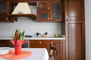 Eine Küche mit Holzausstattung, einer weißen Arbeitsplatte und einem roten Topf mit Pflanzen.