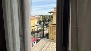 A balcony with a view of a residential area, a red car parked below, and a yellow building in the background. - S347 – Sirolo, delightful two-room apartment with balcony (Sirolo)