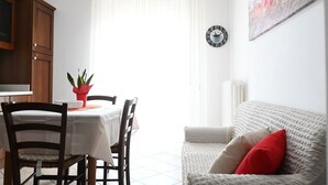 A dining area with a table, chairs, a potted plant, and a sofa. - S347 – Sirolo, delightful two-room apartment with balcony (Sirolo)