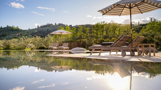 A serene pool area with lounge chairs and umbrellas, surrounded by lush greenery and a clear view of distant hills. - Awesome home in Massa e Cozzile (Massa e Cozzile)
