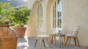 An outdoor patio with two wicker chairs and a small table, surrounded by large windows and potted plants. - Awesome home in Massa e Cozzile (Massa e Cozzile)