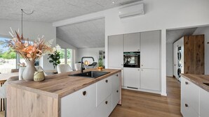 A modern kitchen with a wooden island, white cabinetry, and a built-in oven. - Stunning home in Oksbøl with sauna (Oksbøl)