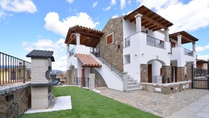 Una casa de dos pisos con fachada de piedra, una escalera de madera y un balcón.