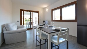 Una cocina moderna con una mesa de comedor preparada para cuatro personas, un sofá y un refrigerador.