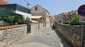 A narrow street with stone walls and a building with a tiled roof. - Amazing apartment in Supetar with WiFi (Supetar)
