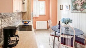 A kitchen with a coffee maker, a bowl of fruit, and a dining area with a table and chairs. - Amazing apartment in Supetar with WiFi (Supetar)