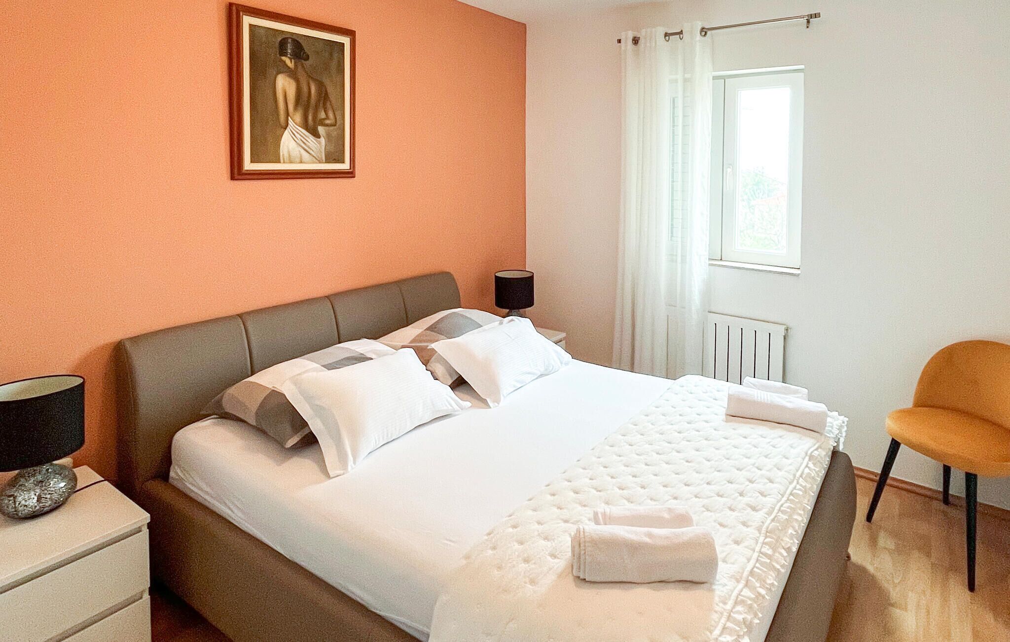 Habitació d'hotel amb llit, una nit, una làmpada, una cadira i un quadre a la paret.