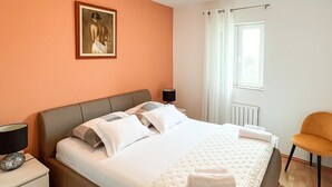 A hotel room with a bed, a nightstand, a lamp, a chair, and a painting on the wall. - Amazing apartment in Supetar with WiFi (Supetar)