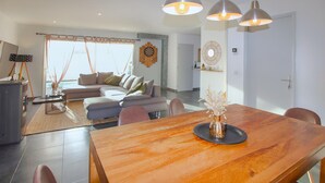 A modern living room with a sectional sofa, a dining table with chairs, and a kitchen area in the background. - Lovely home in Morières-lès-Avignon (Morières-lès-Avignon)