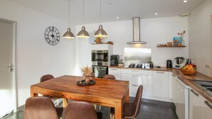 A modern kitchen with a wooden dining table, four chairs, and pendant lights. - Lovely home in Morières-lès-Avignon (Morières-lès-Avignon)