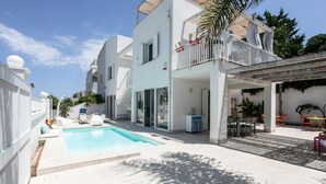 Un immeuble résidentiel moderne doté d’une piscine, d’un espace extérieur aménagé et d’un patio couvert.