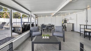 Ein geräumiger Innenbereich mit Esstisch, Stühlen und Sofas. Eine Waschmaschine und eine Uhr sind an der Wand angebracht.