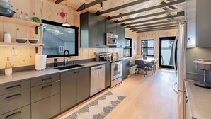 Una cocina moderna con gabinetes grises, electrodomésticos de acero inoxidable y techo de madera.