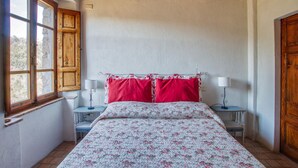 A bedroom with a bed, two bedside tables, a window, and wooden walls.