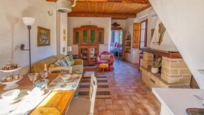 A cozy living room with a wooden ceiling, a dining area with a table set for two, and a fireplace.