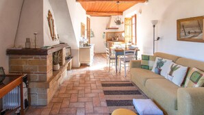 A cozy living room with a fireplace, a dining area, and a kitchen.