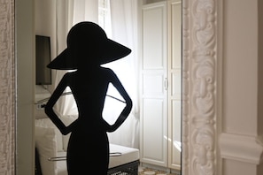 A silhouette of a person in a hat standing in a room with a white door, a white cabinet, and a patterned floor.