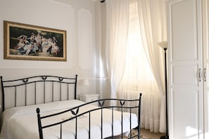 A bedroom with a bed, a painting, a nightstand, a lamp, and a door. - P050 - Porto Recanati, elegant three-room apartment in the historic center (Porto Recanati)