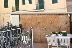 A balcony with a wrought iron railing, a white table with chairs, and a bamboo wall with sunflower decorations. - P050 - Porto Recanati, elegant three-room apartment in the historic center (Porto Recanati)