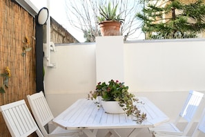 A white outdoor table with a potted plant, two white chairs, and a bamboo wall. - P050 - Porto Recanati, elegant three-room apartment in the historic center (Porto Recanati)