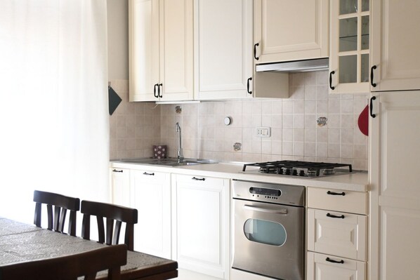 A kitchen with white cabinets, a gas stove, an oven, and a sink. - P050 - Porto Recanati, elegant three-room apartment in the historic center (Porto Recanati)