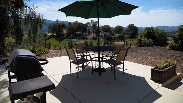 Une terrasse avec une table et des chaises, un barbecue et une vue sur le paysage.