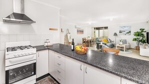 Una cocina moderna con gabinetes blancos, una campana extractora de acero inoxidable y una encimera de granito.