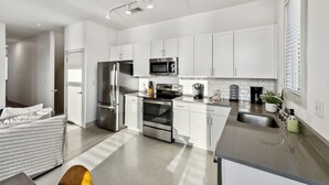 A modern kitchen with white cabinets, stainless steel appliances, and a grey countertop.
