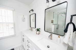 Un baño moderno con dos lavamanos, un espejo grande y una planta en maceta.