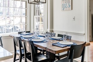 Comedor con una mesa de madera dispuesta para seis personas, rodeado de sillas negras.