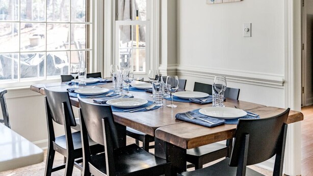 Comedor con una mesa de madera dispuesta para seis personas, rodeado de sillas negras.