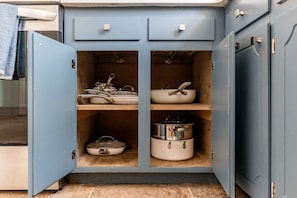 A kitchen with a blue cabinet containing pots and pans.