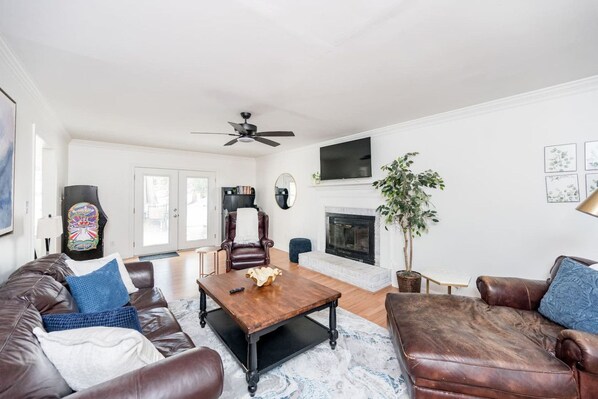 A living room with a fireplace, leather sofas, a coffee table, and a ceiling fan.