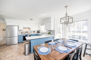 A modern kitchen with white cabinets, a stainless steel refrigerator, and a large island with blue countertops.