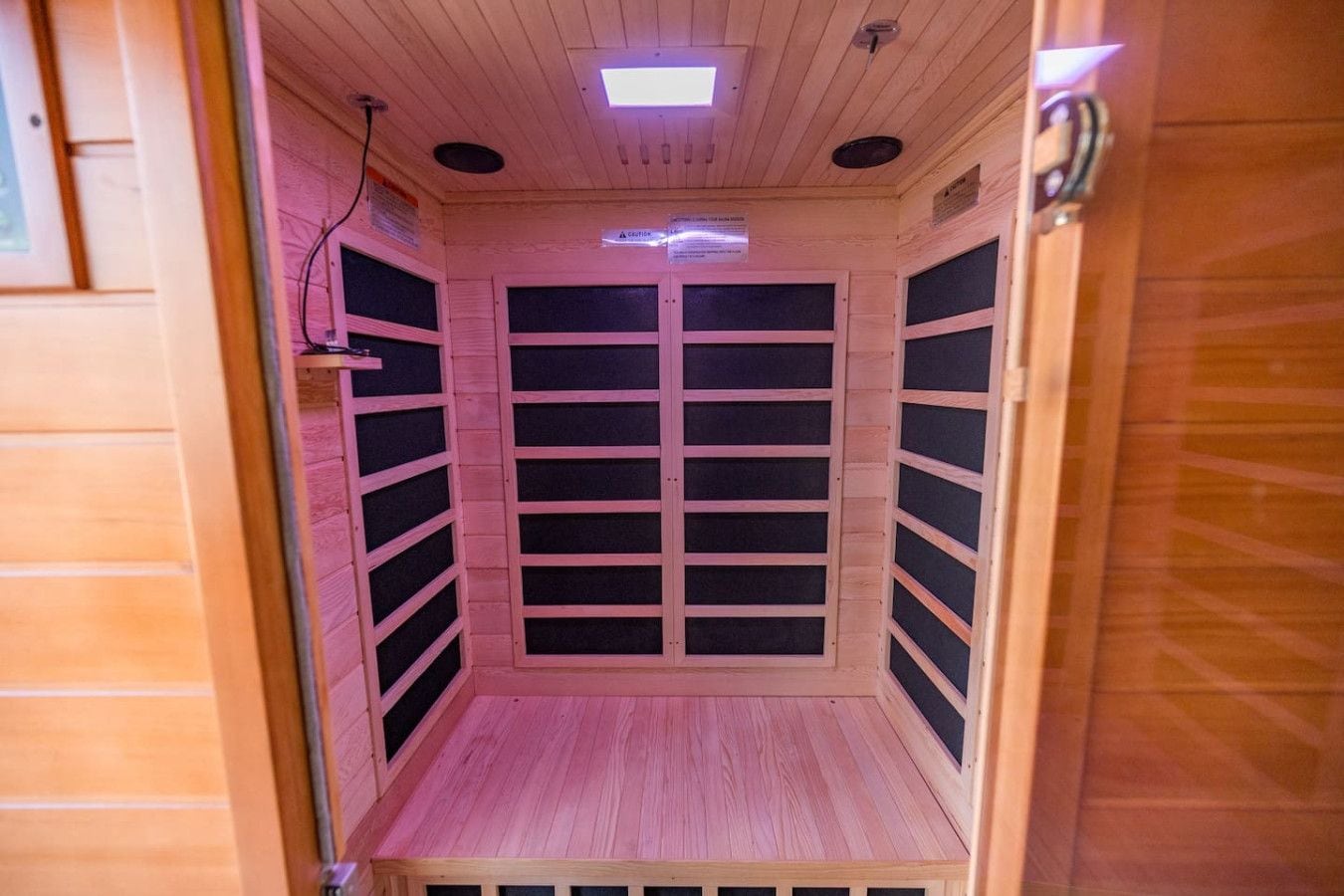 A sauna with a wooden interior, a ceiling light, and a door with a handle.