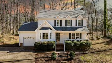 A two-story white house with a dark roof, a front porch, and a garage.