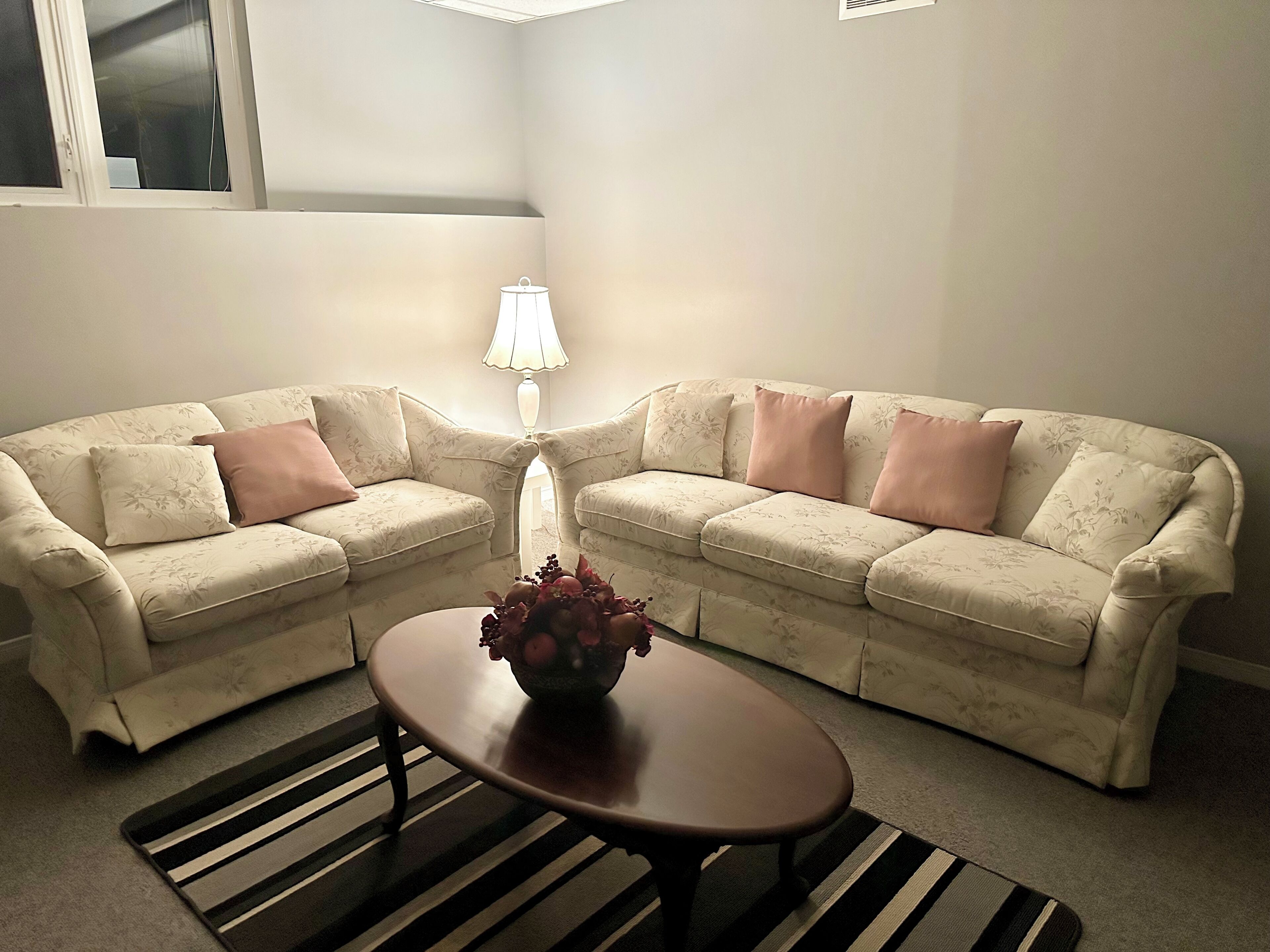 Ein Wohnzimmer mit zwei Sofas, einem Couchtisch und einer Lampe.