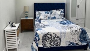 Ein Schlafzimmer mit Bett, Nachttisch, Kleiderschrank und Deckenventilator.