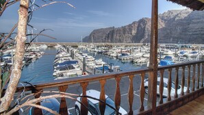 A marina with boats docked, a bridge in the background, and a mountainous landscape.