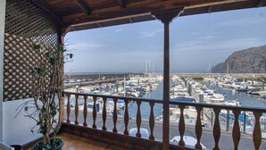 A balcony with a view of a marina, a potted plant, and a wooden railing.