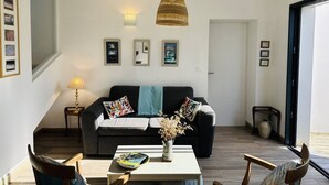 En moderne stue med en mørkegrå sofa, et hvidt sofabord og en hængende lysarmatur i flet.