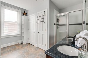 Une salle de bain avec un meuble-lavabo blanc, une douche en verre et un luminaire en forme d’étoile.