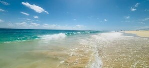 A beach with clear water and a sandy shore.