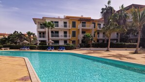 Une piscine à l’eau d’un bleu cristallin, entourée de chaises longues et de palmiers.