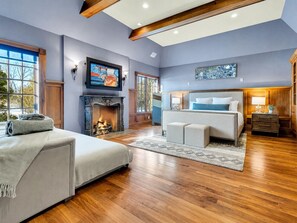 A spacious room with a fireplace, a bed, a sofa, and a television. - Baronwood Oasis | Pool + Arcade Mega Estate (Sheboygan)
